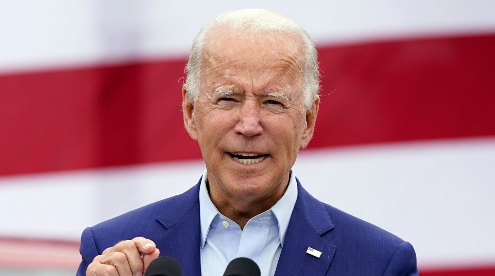 Joe Biden, presidente dos Estados Unidos, falando em microfones, gesticulando, de roupa social azul