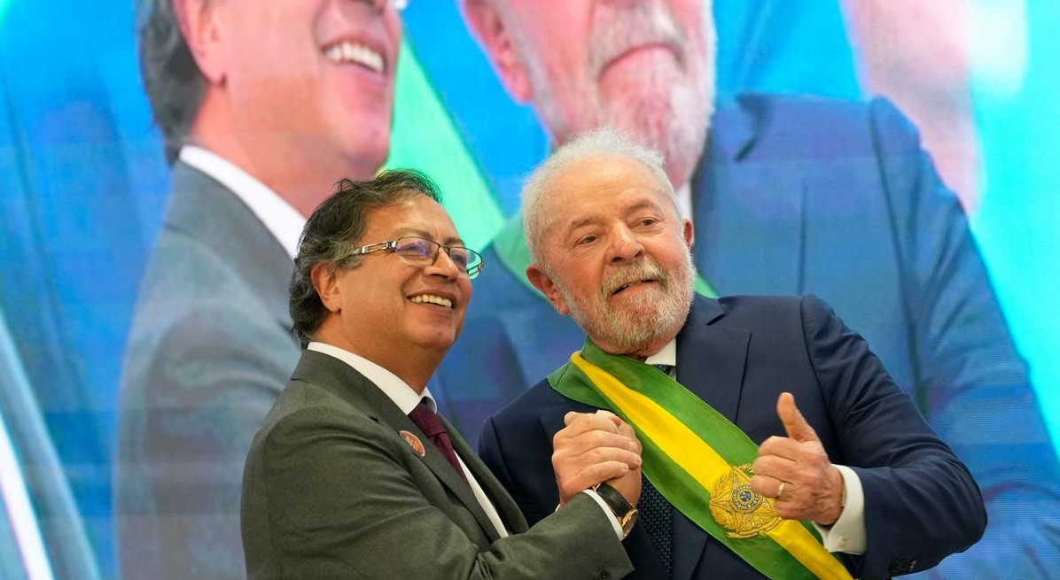 Gustavo Petro e Lula sorrindo e apertando as mãos, sem olhar para a câmera