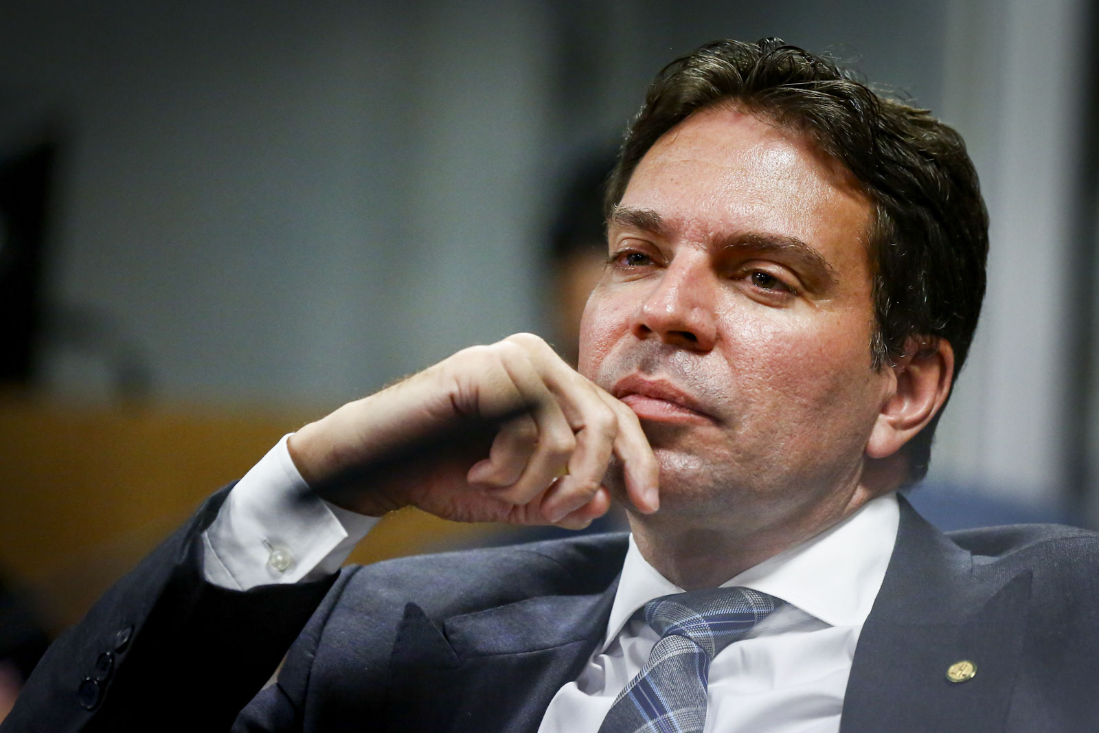 O deputado Alexandre Ramagem com expressão pensativa e mão no queixo, sem olhar para a câmera