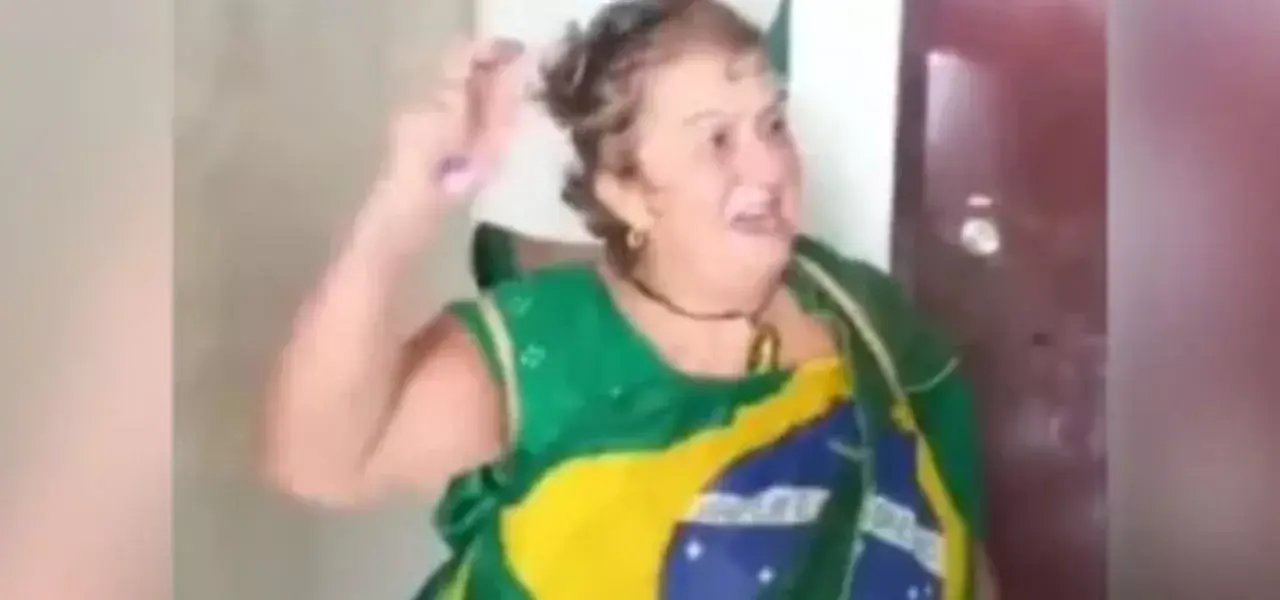 Fátima de Tubarão ao centro de montagem, vestida com as cores da bandeira brasileira, gritando com braço levantado