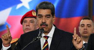 O presidente da Venezuela, Nicolás Maduro, falando em microfone e apontando pra cima com as duas mãos