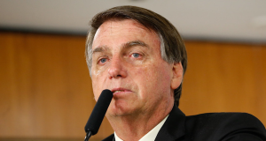 O ex-presidente Jair Bolsonaro chorando e falando em microfone, sem olhar para a câmera