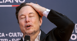 Elon Musk com a mão na cabeça e olhos fechados com expressão de preocupação