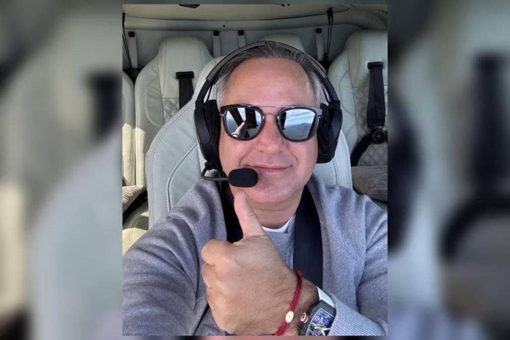 O empresário Boris Maciel Padilha fazendo sinal de joia de óculos escuros e fone dentro de aeronave, sem sorrir