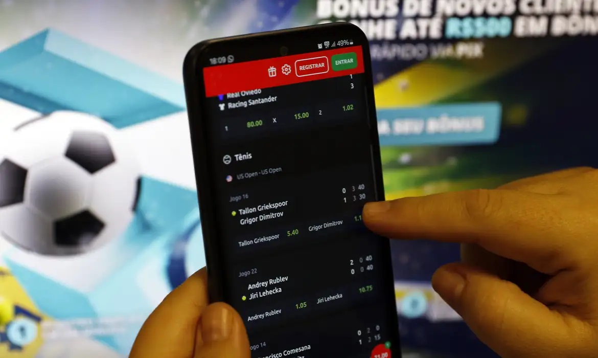 Mão mexendo em celular aberto em aplicativo de casa de aposta