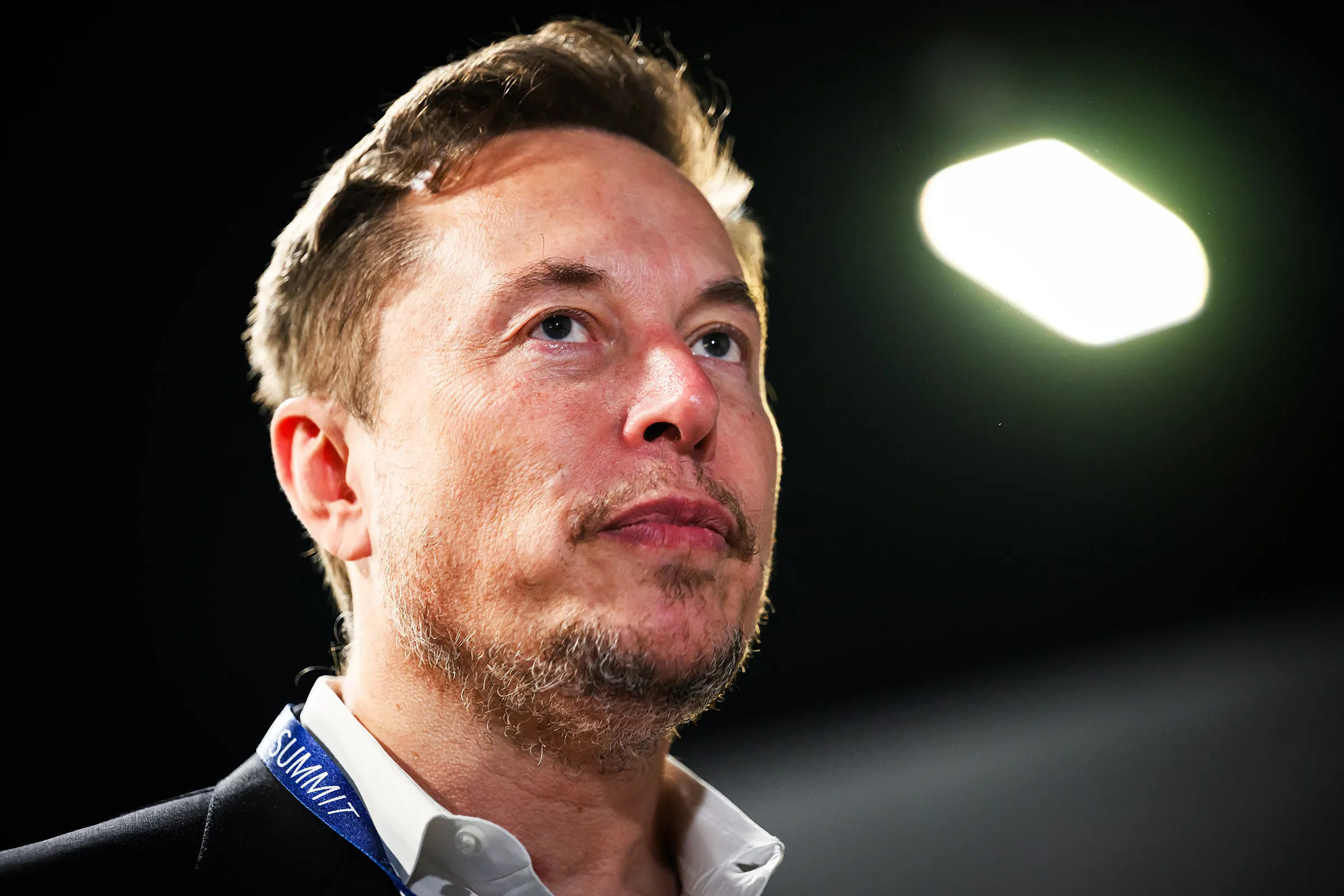 Elon Musk em close, sério, olhando para cima