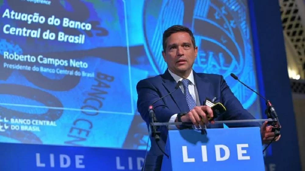 O presidente do Banco Central, Roberto Campos Neto, discursando, sério, em pé, sem olhar para a câmera