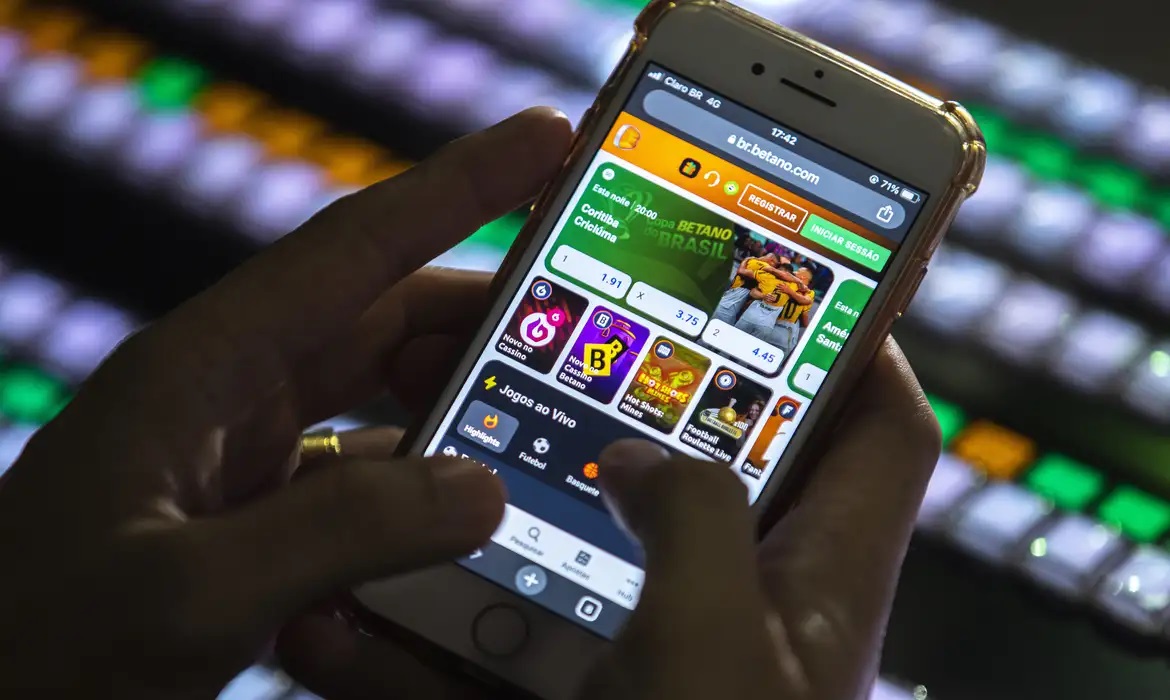 Mãos com celular e aplicativos de jogos de azar abertos