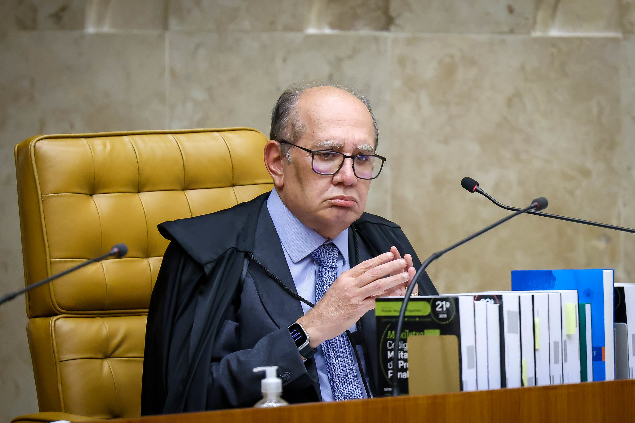 Gilmar Mendes com expressão de chateação, de óculos, com as mãos unidas