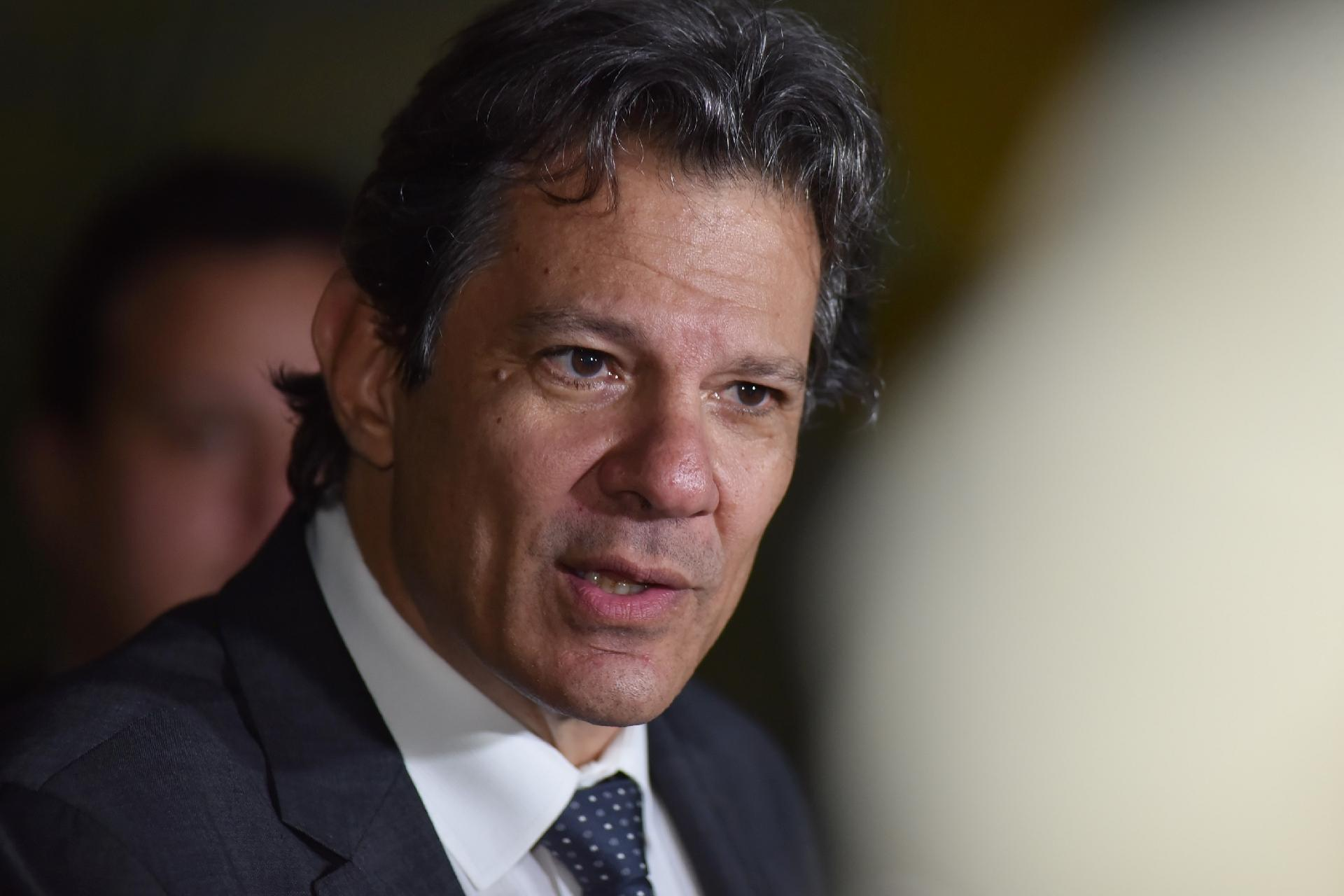 Fernando Haddad falando com expressão séria, sem olhar para a câmera