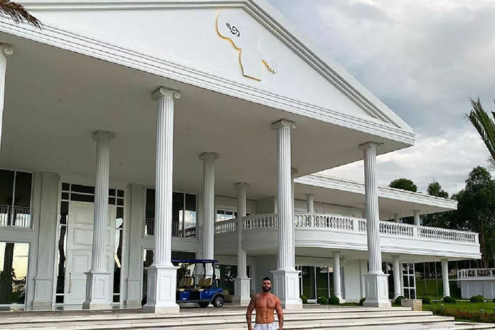 Gusttavo Lima em pé, sem camisa, na frente de mansão de Goiânia