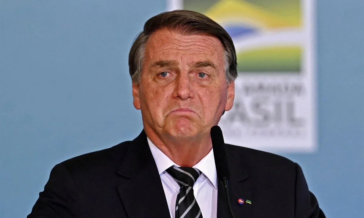 O ex-presidente Jair Bolsonaro (PL) com cara de choro, perto de microfone, sem olhar para a câmera