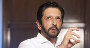Ricardo Nunes de camisa social branca, gesticulando e olhando para o lado, sério