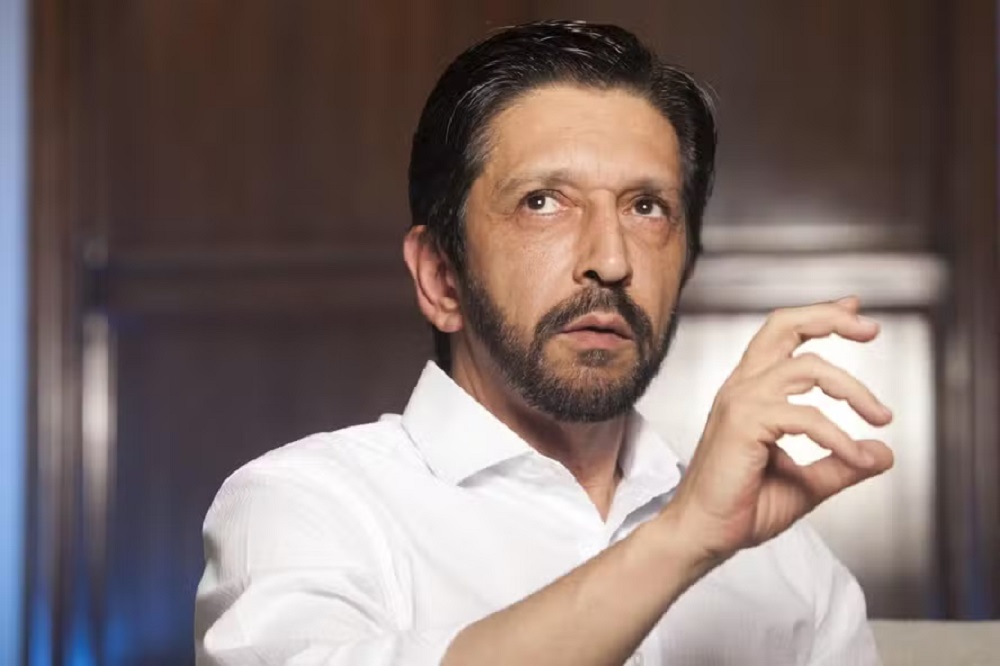 Ricardo Nunes de camisa social branca, gesticulando e olhando para o lado, sério