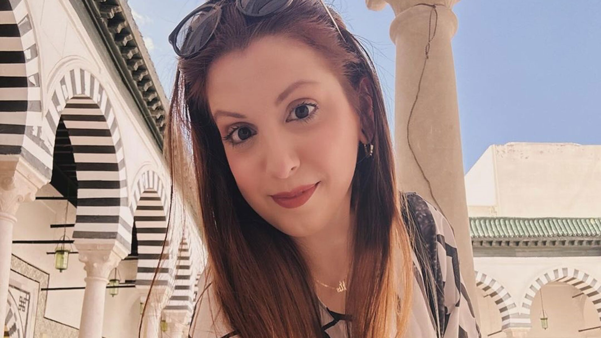 jornalista Nathalia Urban em selfie de cabelo solto, com óculos escuros na cabeça, sem sorrir