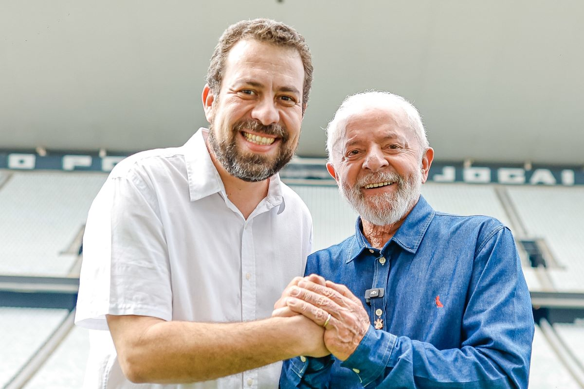 Guilherme Boulos e Lula sorrindo de mãos dadas para foto
