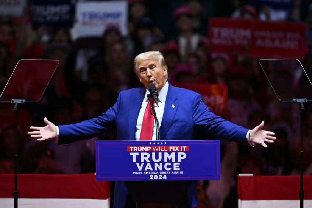 Donald Trump no Madison Square Garden, em Nova York, falando, com os braços abertos
