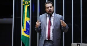 O candidato Guilherme Boulos (PSOL) na Câmara dos Deputados, falando e gesticulando com expressão séria