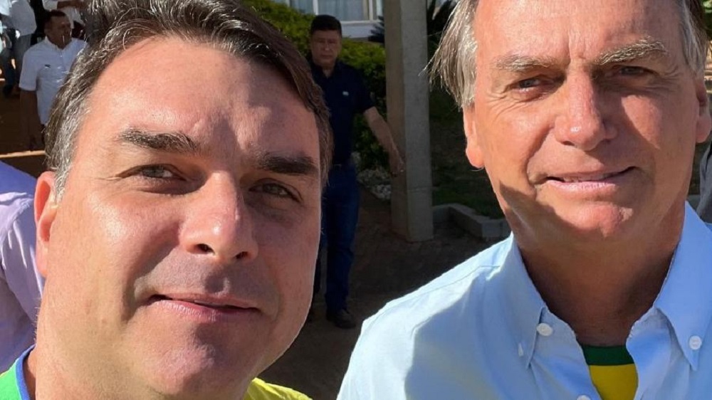 Flávio Bolsonaro e Jair Bolsonaro posando para selfie sem sorrir