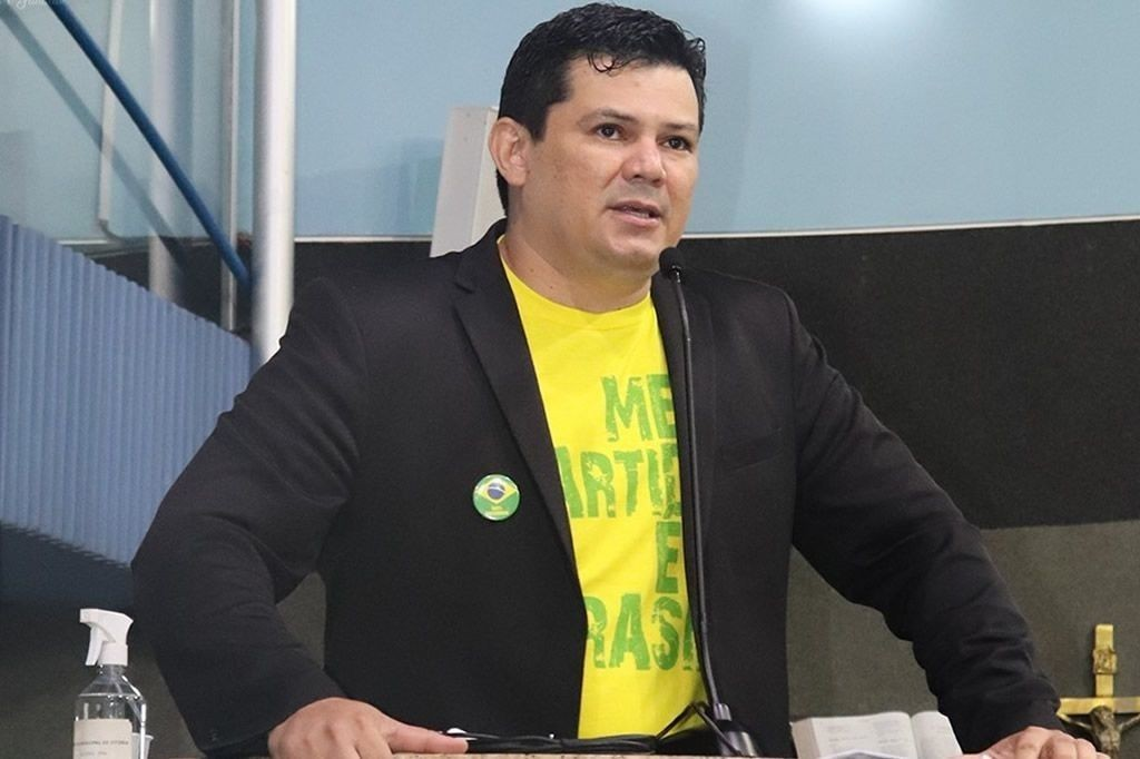 deputado Gilvan da Federal (PL-ES) de blusa amarela e paletó preto, com expressão pensativa, sem olhar para a câmera