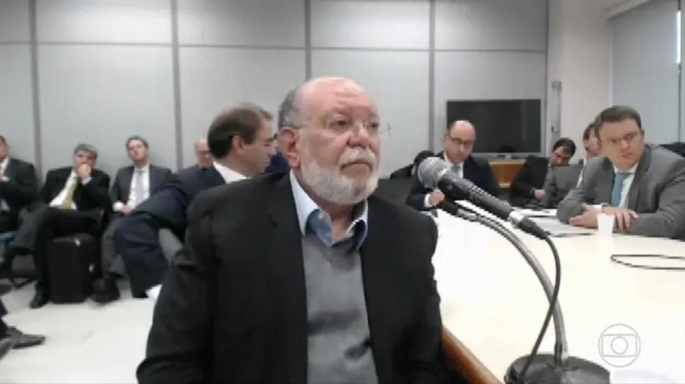 Léo Pinheiro sério, perto de microfone, sem olhar para a cãmera