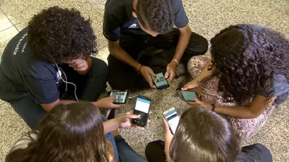 Adolescentes em rodinha mexendo no celular