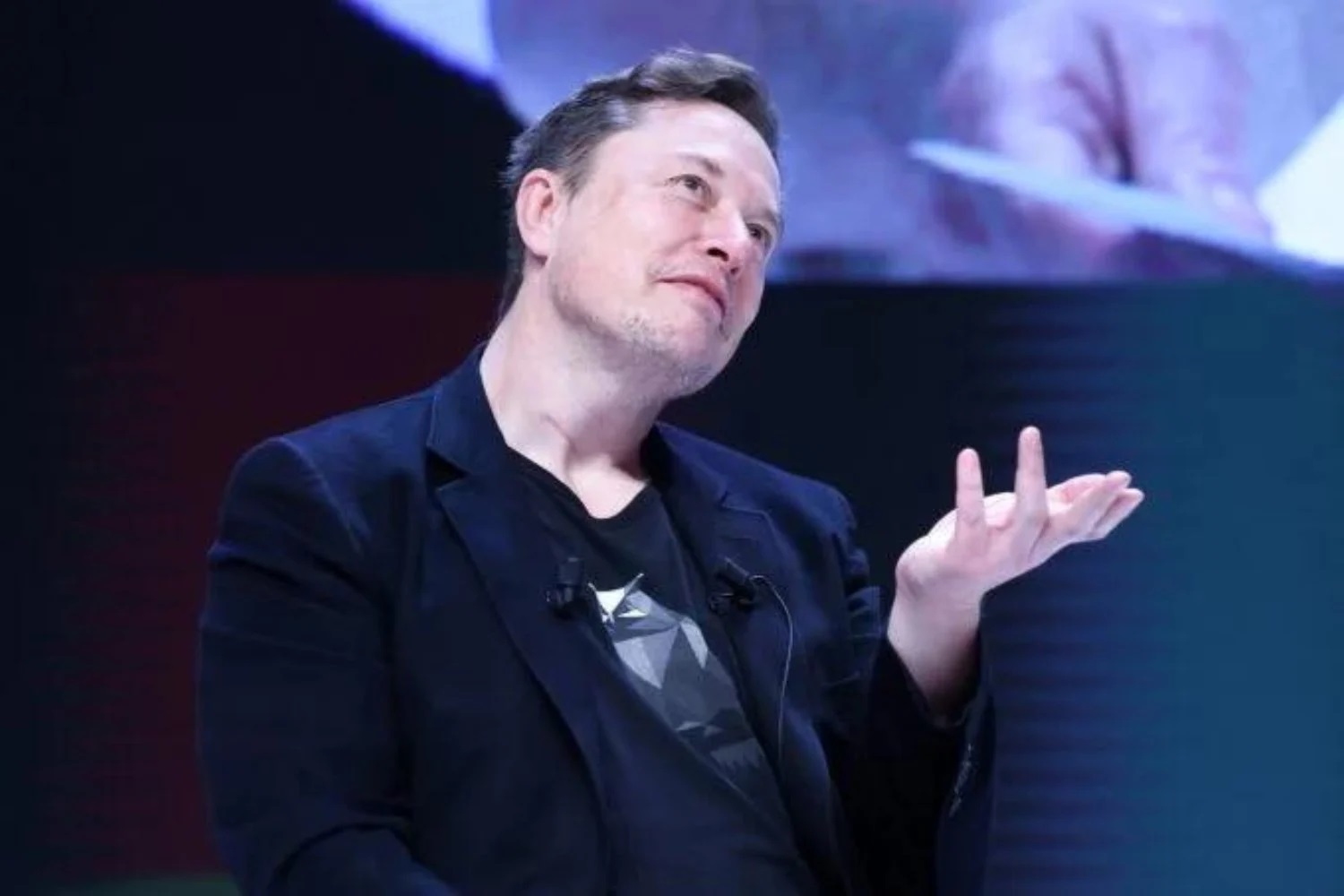 Elon Musk falando e gesticulando com expressão pensativa