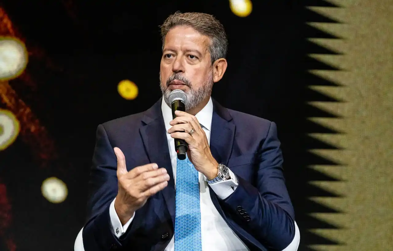 Arthur Lira falando em microfone e gesticulando, sério, olhando para o lado