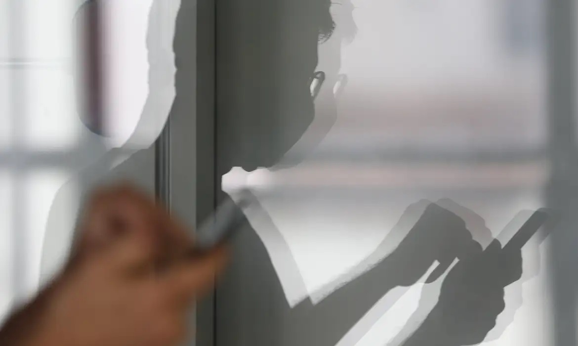 Sombra de homem mexendo no celular