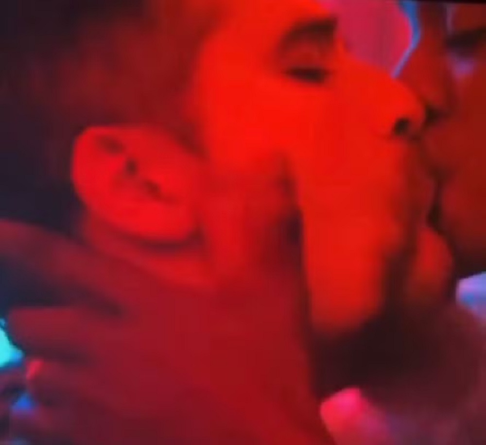 Bruno Gagliasso e Patrick Congo se beijando em cena da série 'Os quatro da Candelária', com iluminação vermelha