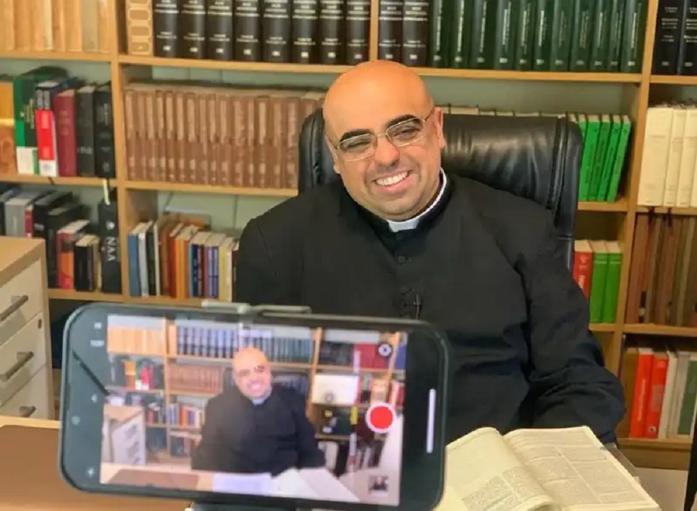 Padre José Eduardo de Oliveira e Silva gravando vídeo e sorrindo
