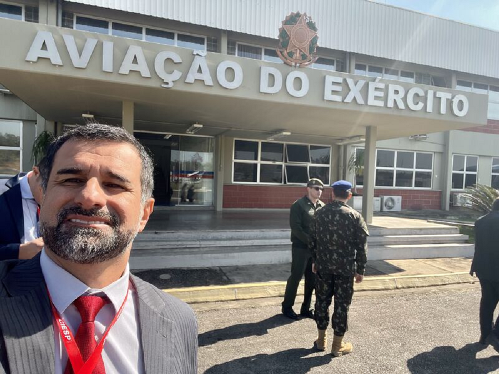 coronel da reserva Anderson Freire Barboza fazendo selfie sorrindo perto de espaço de aviação do Exército