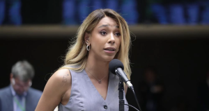 deputada federal Erika Hilton (PSOL) de roupa cinza sem mangas e cabelo solto, falando em microfone