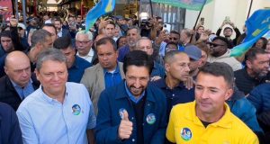 Diogo Costa Cangerana aparece no centro de foto, atrás de Tarcísio de Freitas e Ricardo Nunes, em evento