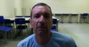 Marcos Herbas William Camacho, mais conhecido como Marcola, de camiseta azul, olhando para frente e falando, com cadeiras e mesas atrás