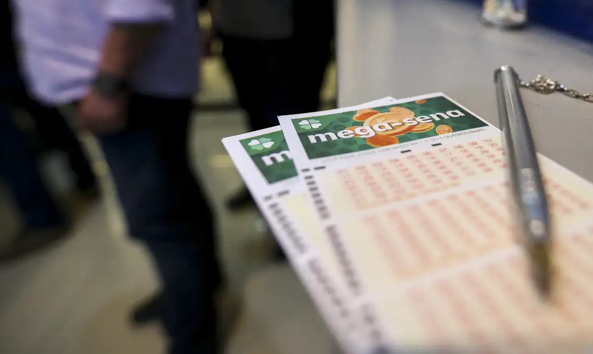 Bilhetes da mega-sena em primeiro plano, com caneta