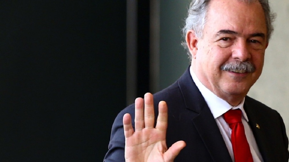 Aloizio Mercadante, presidente do BNDES, sorrindo e acenando, de terno e gravata