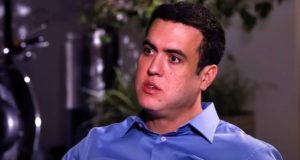 Vinicius Gritzbach de camisa social azul, falando e olhando para o lado, sério