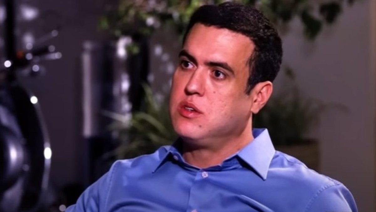 Vinicius Gritzbach de camisa social azul, falando e olhando para o lado, sério