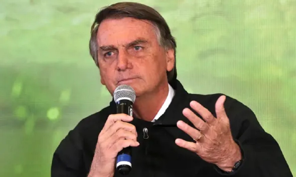 ex-presidente Jair Bolsonaro (PL) de casaco preto, falando em microfone e gesticulando, sério
