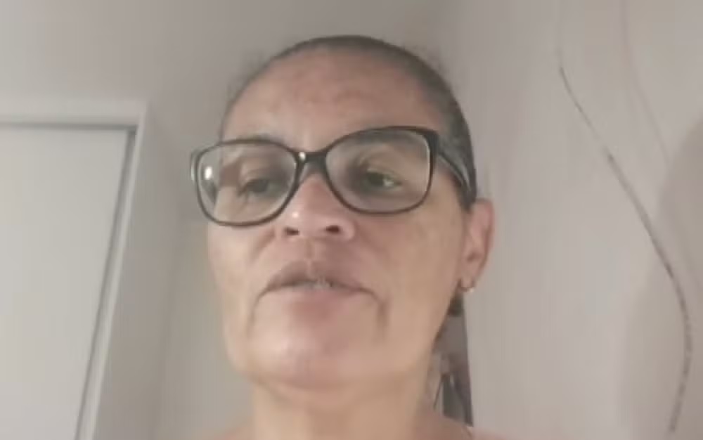 A professora Sueli Santana de óculos e cabelo preso, falando, sem olhar para a câmera, em close