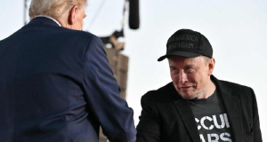Donald Trump e Elon Musk em aperto de mãos, o primeiro de costas