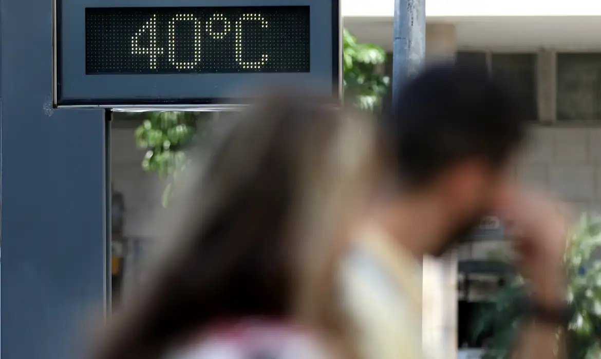 Relógio marcando 40 graus com pessoas desfocadas na frente