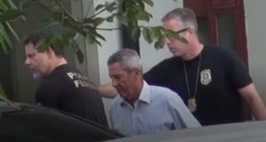 general Walter Braga Netto cabisbaixo, acompanhado de agentes