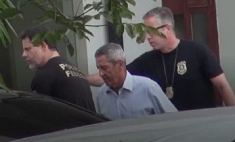 general Walter Braga Netto cabisbaixo, acompanhado de agentes