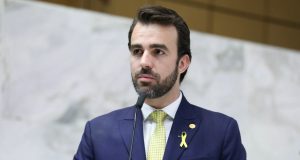 O deputado estadual bolsonarista Lucas Bove (PL) olhando pra frente, sem olhar pra câmera, sério, de roupa social azul marinho