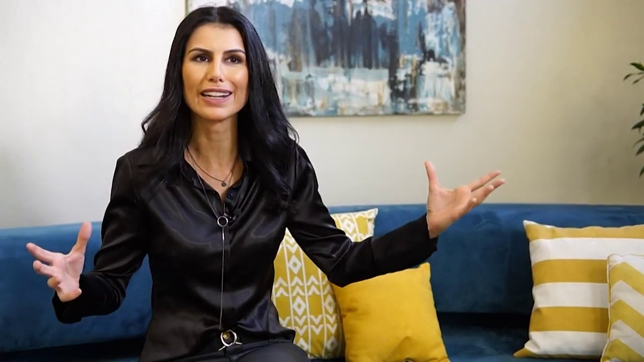 Cleisla Garcia de roupa preta e cabelo solto, falando e gesticulando com os braços abertos