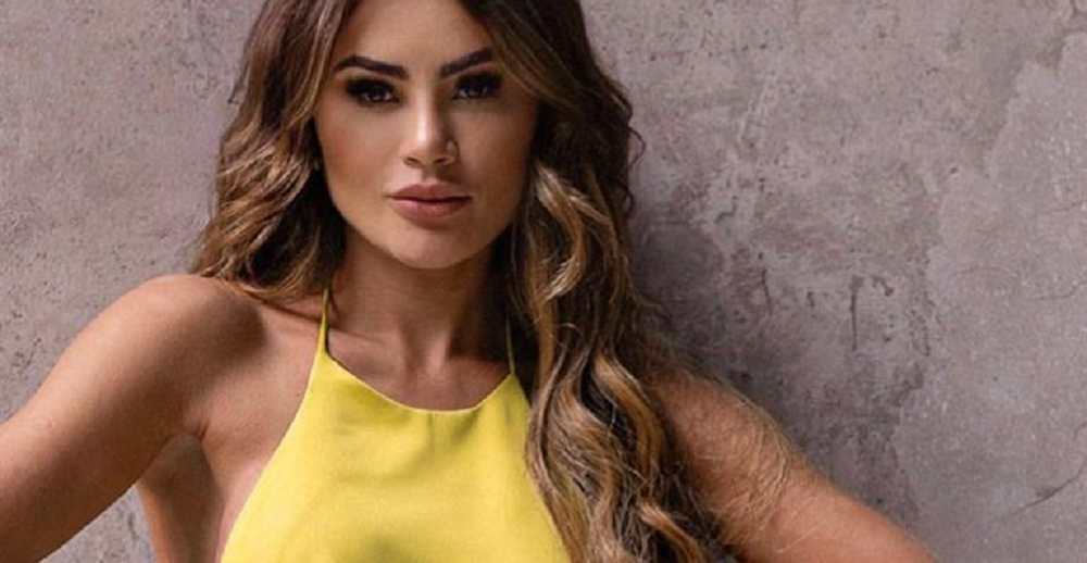 Natacha Horana em close, de roupa amarela e cabelo solto, fazendo carão para a câmera