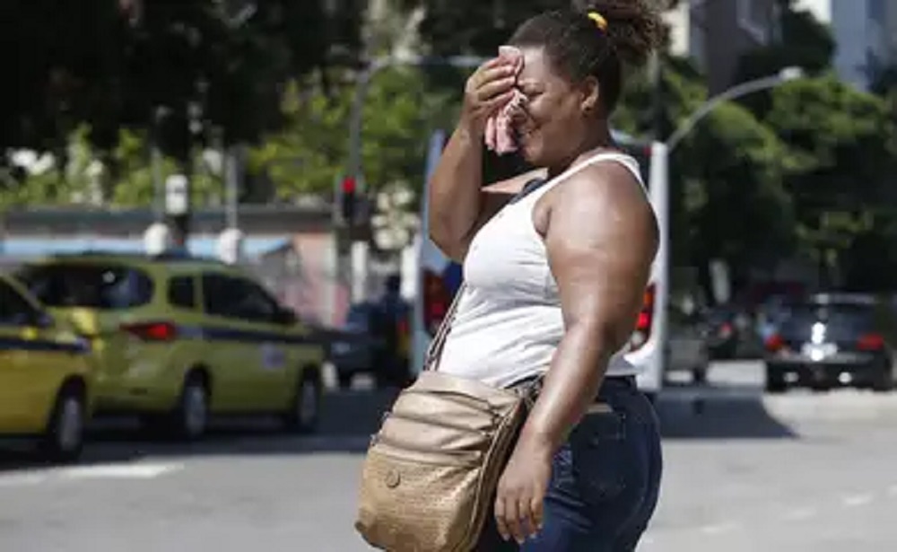 Mulher na rua tentando se proteger do sol com toalhinha