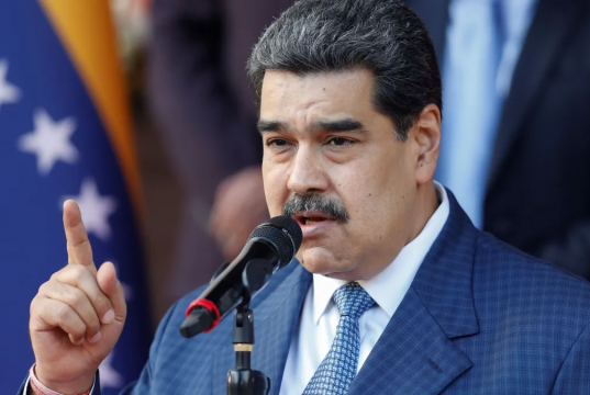 Nicolás Maduro falando em microfone, sério, apontando pra cima